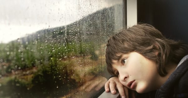 boy looking out a rainy window