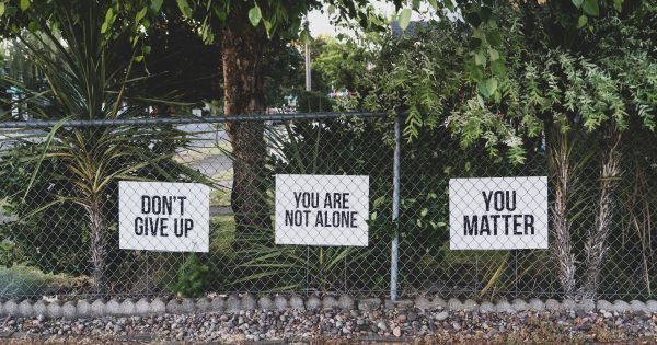 Signs on a chain link fence: Don't give up, You are not alone, You matter