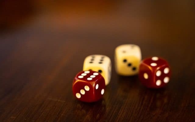 four six-sided dice sitting on the table. Two dice are red and two are white.