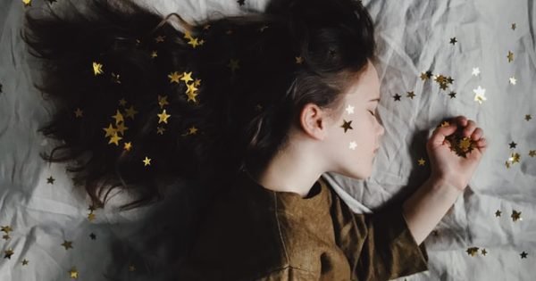 a girl sleeping on a bed covered in stars