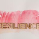 the word resilience in wooden letters on a water color paint background