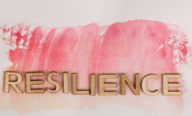 the word resilience in wooden letters on a water color paint background