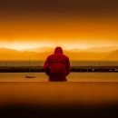 man watching sunset in front of water