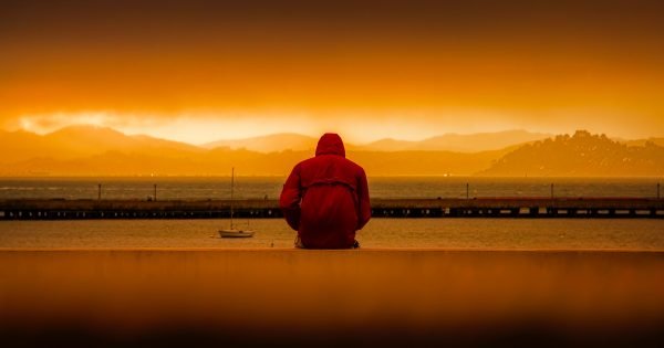 man watching sunset in front of water
