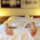 person resting in bed with only feet showing out of the covers