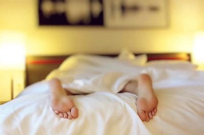 person resting in bed with only feet showing out of the covers