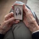 Elderly woman holding a picture of her younger self