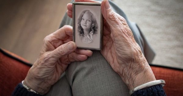 Elderly woman holding a picture of her younger self