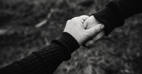 black and white photo of two people holding hands