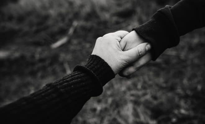 black and white photo of two people holding hands