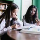 two school students sitting at a table with textbooks