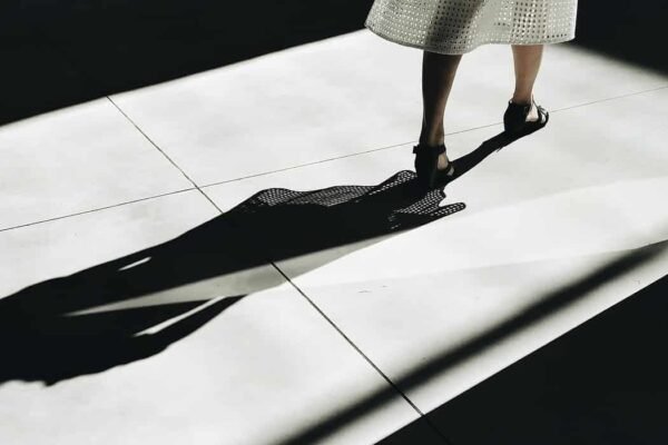 woman in a dress walking with a shadow behind her