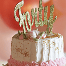 birthday cake with pink and white icing and gold glitter topper with forty in front of pink and red balloons in background