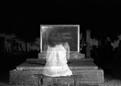 ghost girl sitting in front of headstone