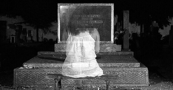 ghost girl sitting in front of headstone