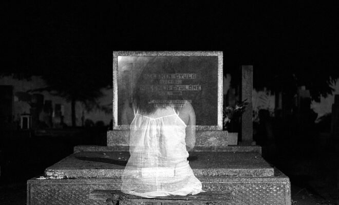 ghost girl sitting in front of headstone
