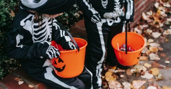 two costumed kids with Halloween buckets trick or treat.