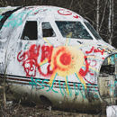 broken airplane abandoned in the forest with colorful graffiti sprayed on it