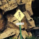 A road sign shows an alien crossing in front of a rock wall