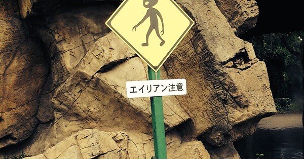 A road sign shows an alien crossing in front of a rock wall