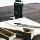 A quail pen on a paper beside an ink bottle