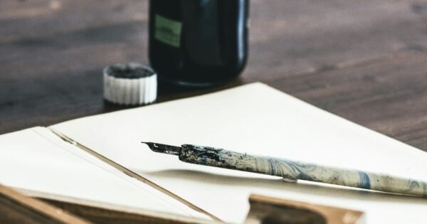 A quail pen on a paper beside an ink bottle