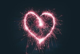 A red heart, drawn by a sparkler, briefly crackles against the dark