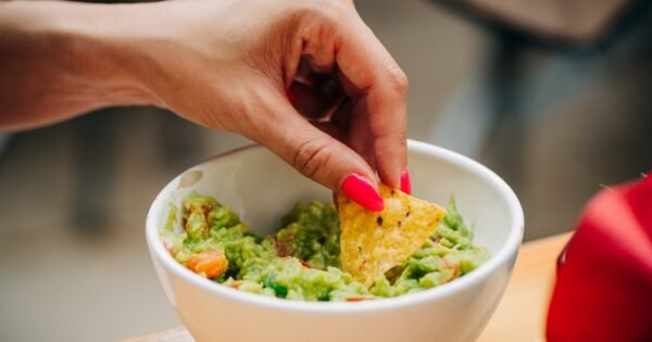 woman's hand dipping chip into dip