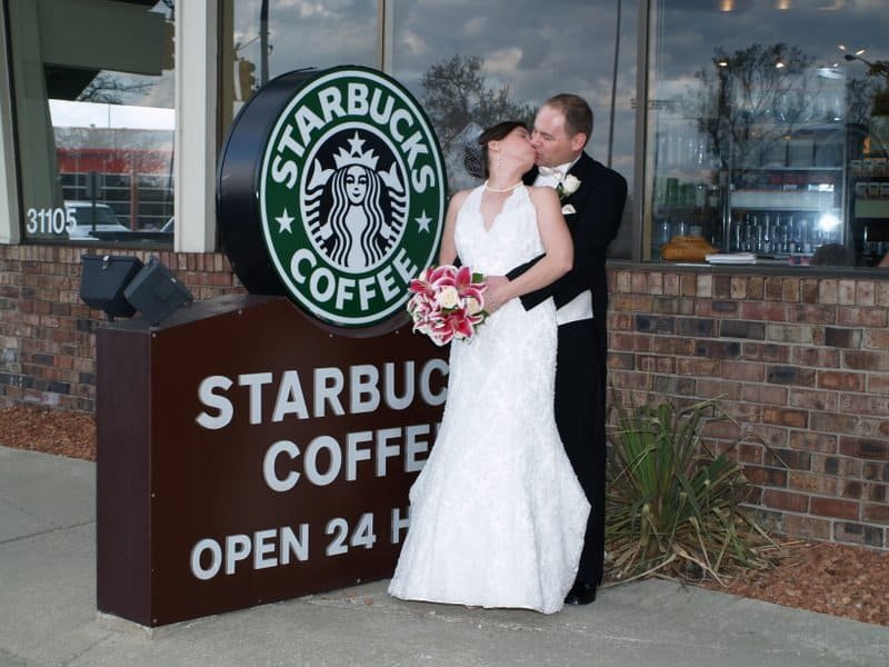 bride and groom kissing in front of Starbucks sign