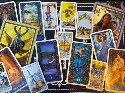 A selection of Tarot cards fading from the Tower, Hierophant, and Six of Swords on the left, the Wheel of Fortune in the center, and the Ten of Cups, Lovers, and the World on the right.