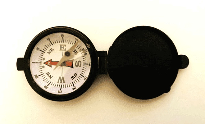 Black trimmed compass laying on a cream white background