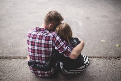Father and daughter embracing while sitting on a step outside