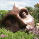 large broken mask in a field of green bushes and wildflowers