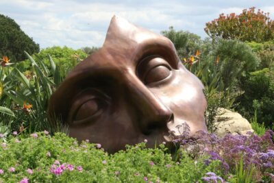 large broken mask in a field of green bushes and wildflowers