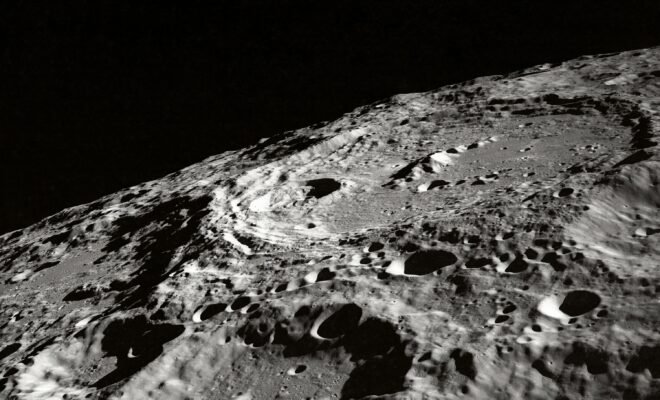 The surface of the moon looms in the lower right quadrant, dominated by two large craters and pockmarked by many smaller ones