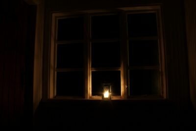 lit candle sitting on a windowsill at night