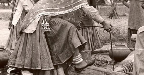 Photograph of 1950s India village women dressed in traditional clothes collecting water at the village well.
