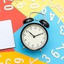 notepad and clock on colorful background with various numbers splatters across.