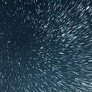 Stars trails along the periphery blur against the dark background of deep space creating a cosmic tunnel to travel through.