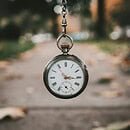 a bronze pocket watch hanging from a chain in front of an urban background