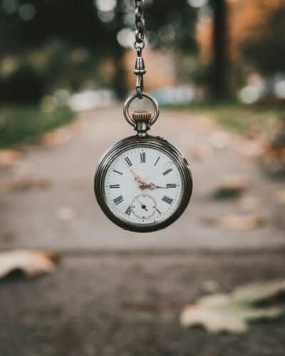 a bronze pocket watch hanging from a chain in front of an urban background