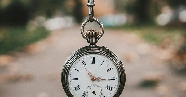 a bronze pocket watch hanging from a chain in front of an urban background