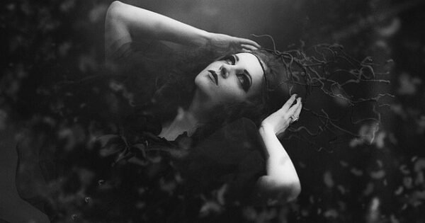 a woman gazing upward in a dark landscape