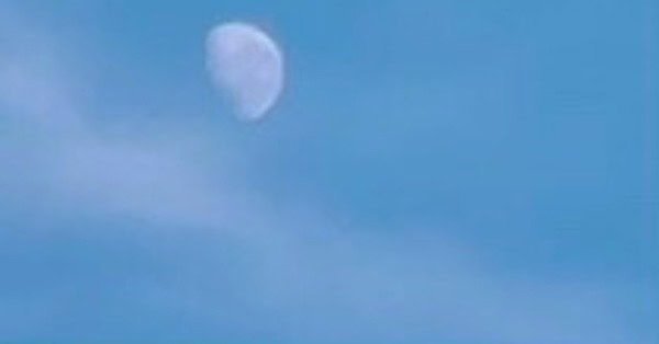 The image is of a three quarter moon in a misty daytime sky