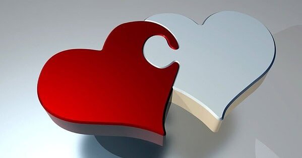 Two hearts, one red and one white, joined together like a puzzle piece