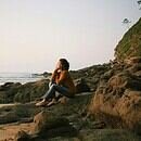 A lady sitting on rocks thinking