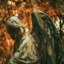 An autumn forest background with an angel made from stone.