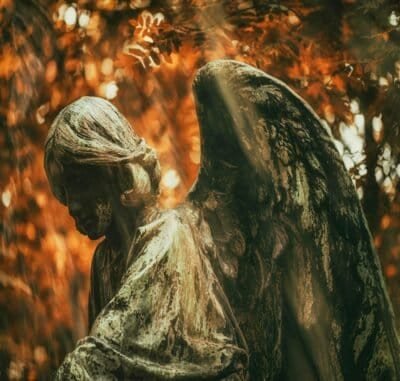 An autumn forest background with an angel made from stone.