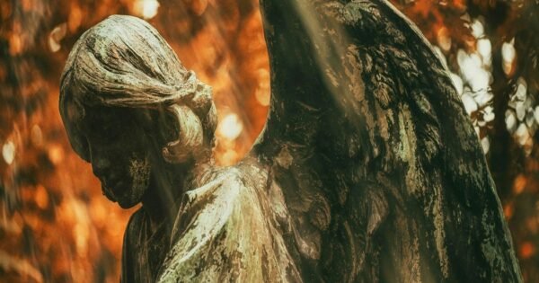 An autumn forest background with an angel made from stone.