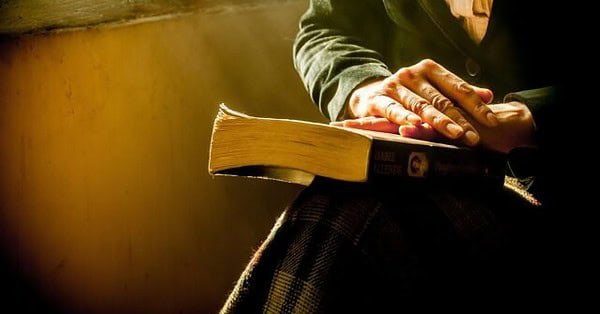 Woman folding hands on a book